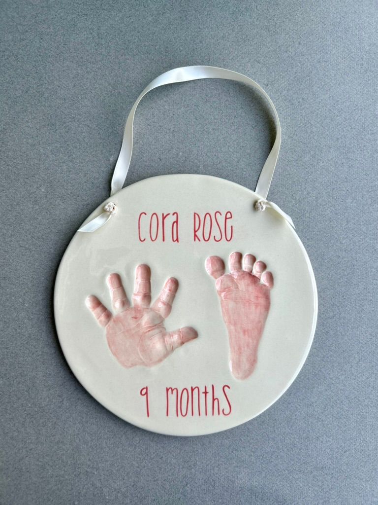 Pink hand and footprint plaque labeled 'Cora Rose, 9 months.'