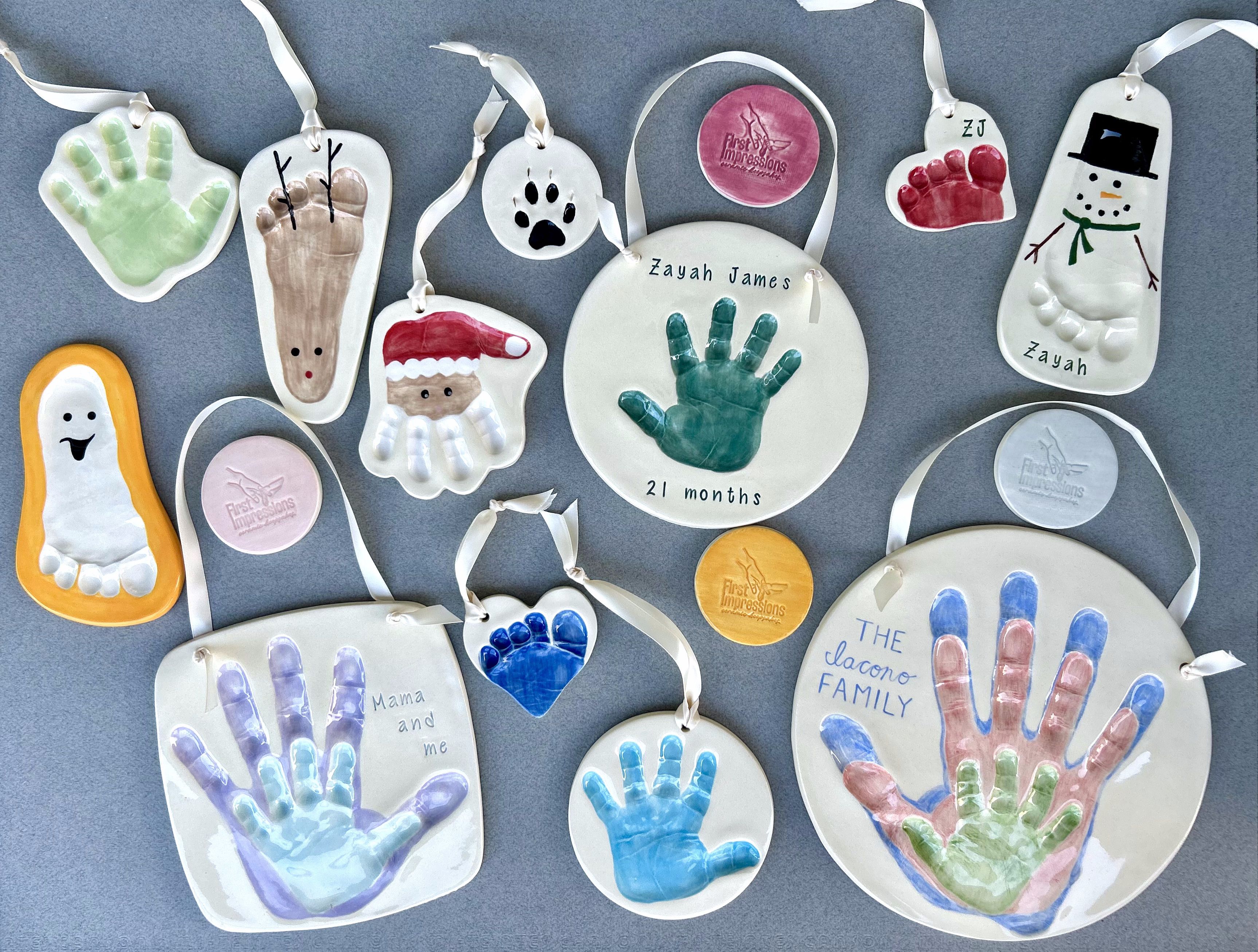A spread of finished ceramic keepsakes: handprints, footprints, ornaments, and a family plaque.