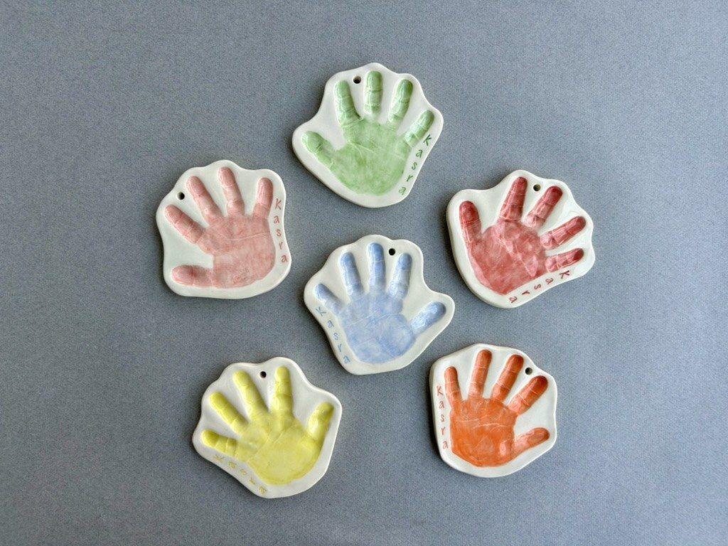 A set of pastel handprint ceramic ornaments laid out in a row.