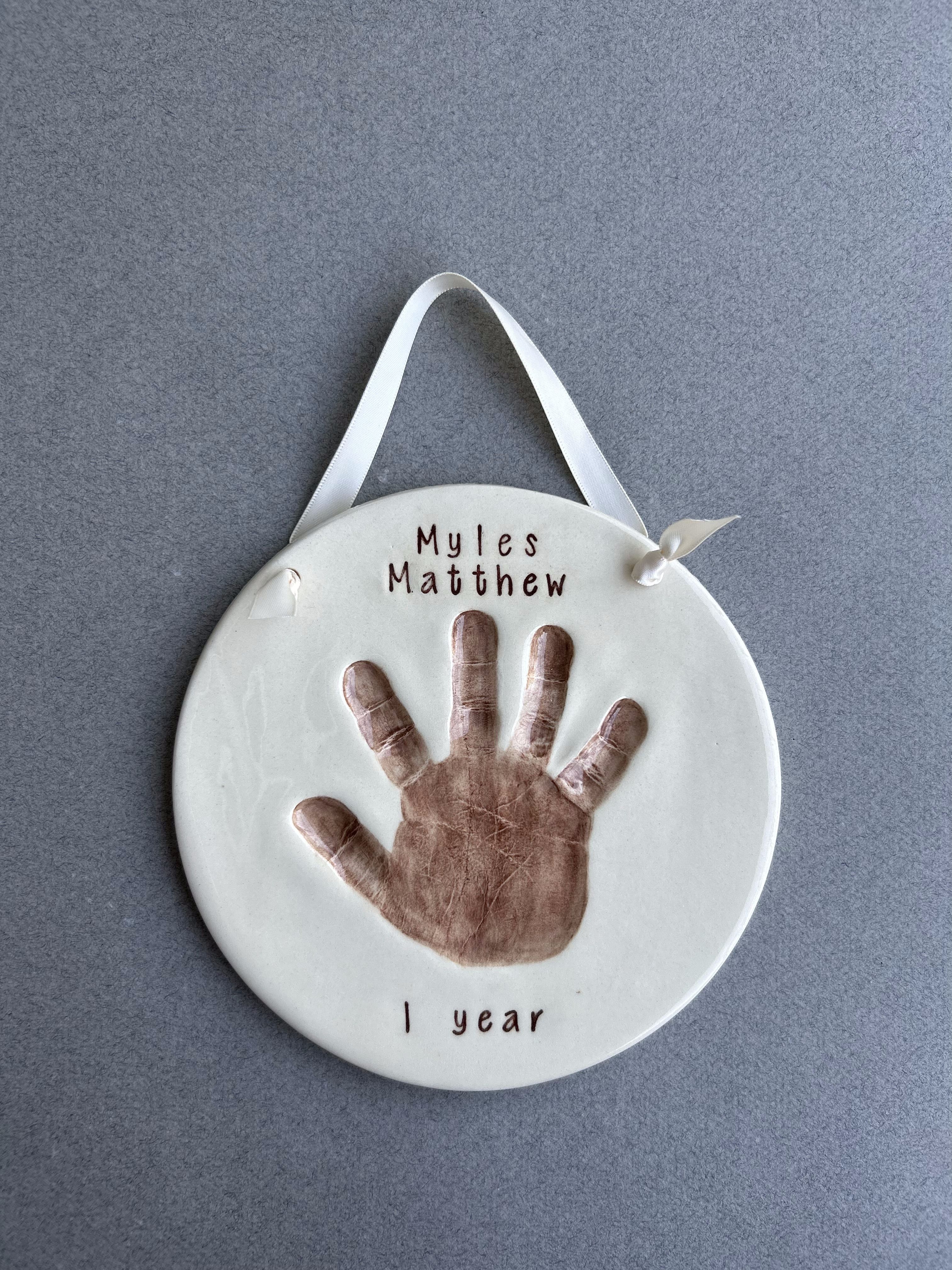 Single ceramic handprint plaque hand-labeled 'Myles Matthew, 1 year.'